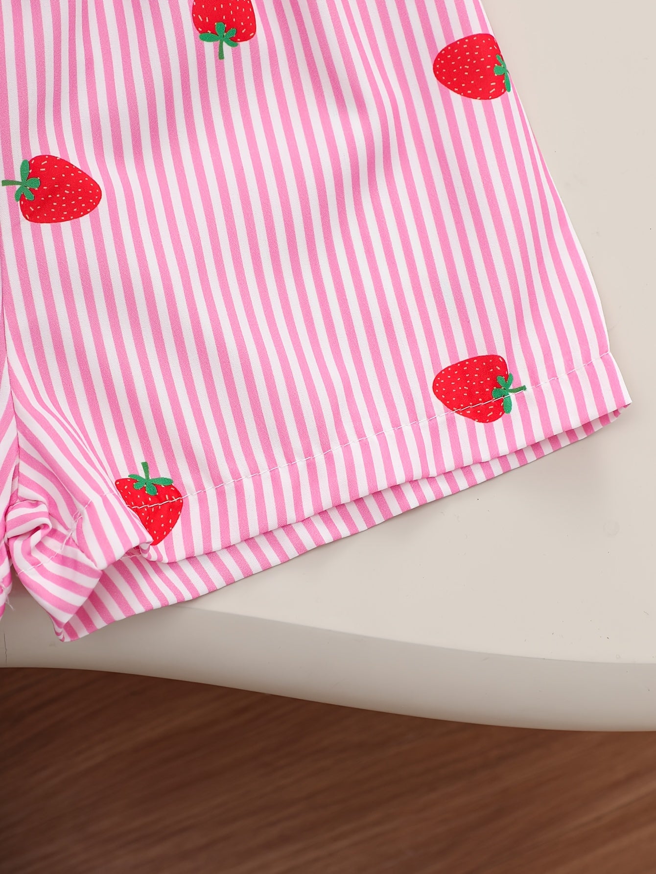 A Two-Piece Set. A Tank Top And Shorts Outfit Featuring Strawberry Prints, Striped Patterns, Bow Decorations, And a Ruffled Hem Design. This Is a Casual Summer Outfit for Girls. It Makes a Great Gift for Girls' Clothing. Suitable for Outdoor Wear