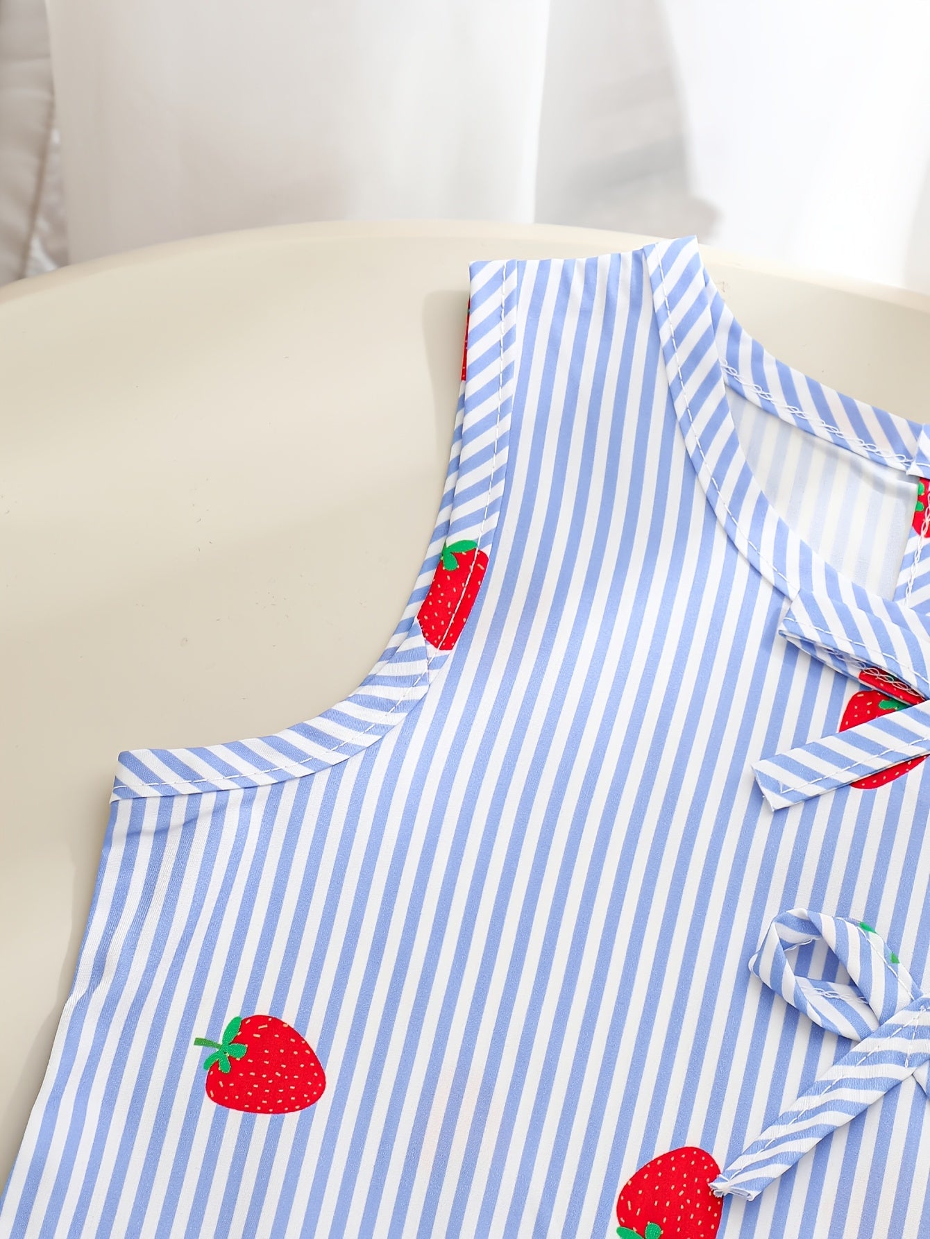 A Two-Piece Set. A Tank Top And Shorts Outfit Featuring Strawberry Prints, Striped Patterns, Bow Decorations, And a Ruffled Hem Design. This Is a Casual Summer Outfit for Girls. It Makes a Great Gift for Girls' Clothing. Suitable for Outdoor Wear