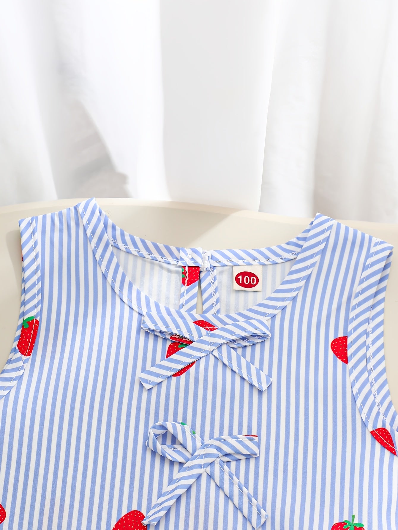 A Two-Piece Set. A Tank Top And Shorts Outfit Featuring Strawberry Prints, Striped Patterns, Bow Decorations, And a Ruffled Hem Design. This Is a Casual Summer Outfit for Girls. It Makes a Great Gift for Girls' Clothing. Suitable for Outdoor Wear