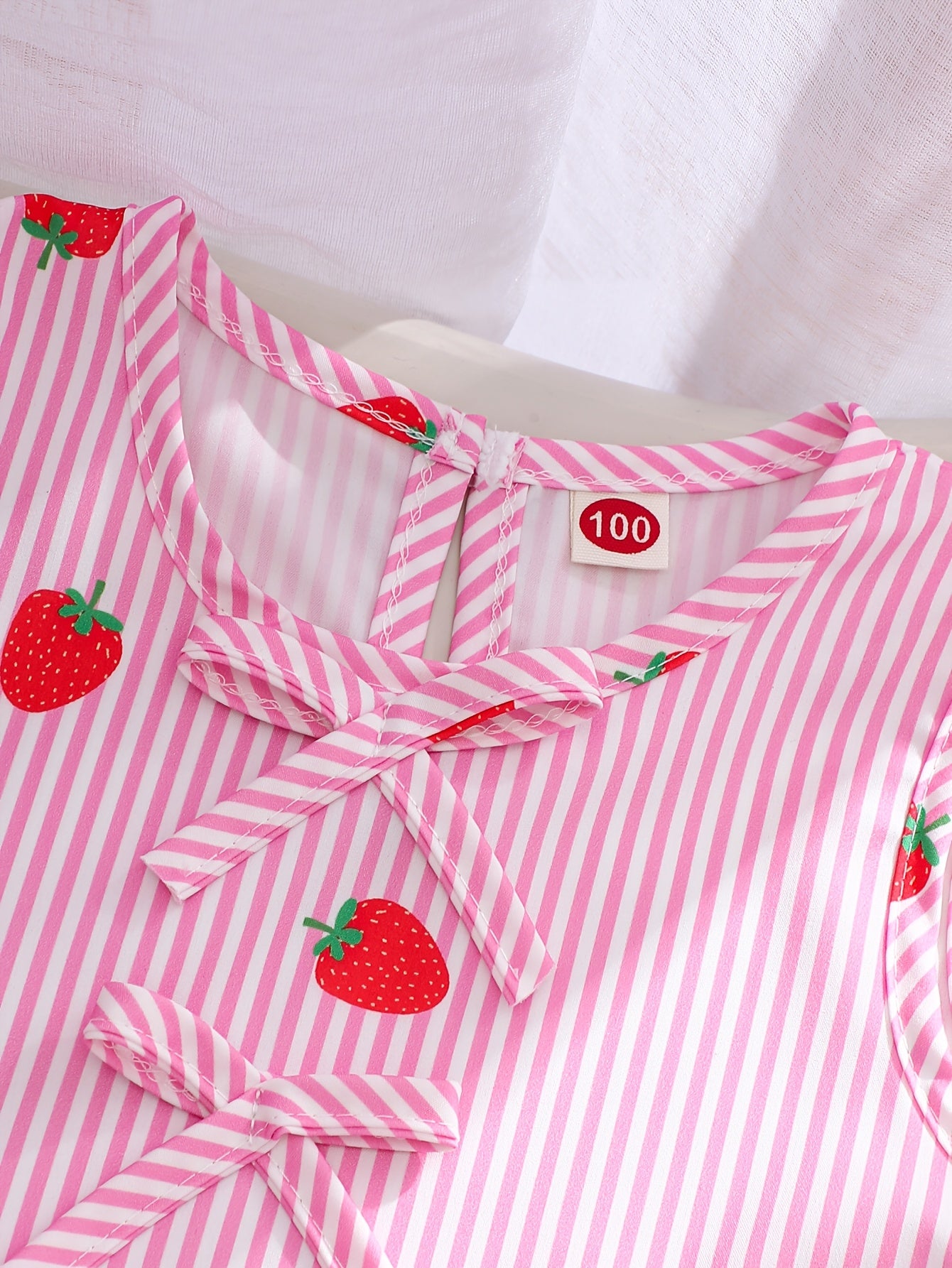 A Two-Piece Set. A Tank Top And Shorts Outfit Featuring Strawberry Prints, Striped Patterns, Bow Decorations, And a Ruffled Hem Design. This Is a Casual Summer Outfit for Girls. It Makes a Great Gift for Girls' Clothing. Suitable for Outdoor Wear