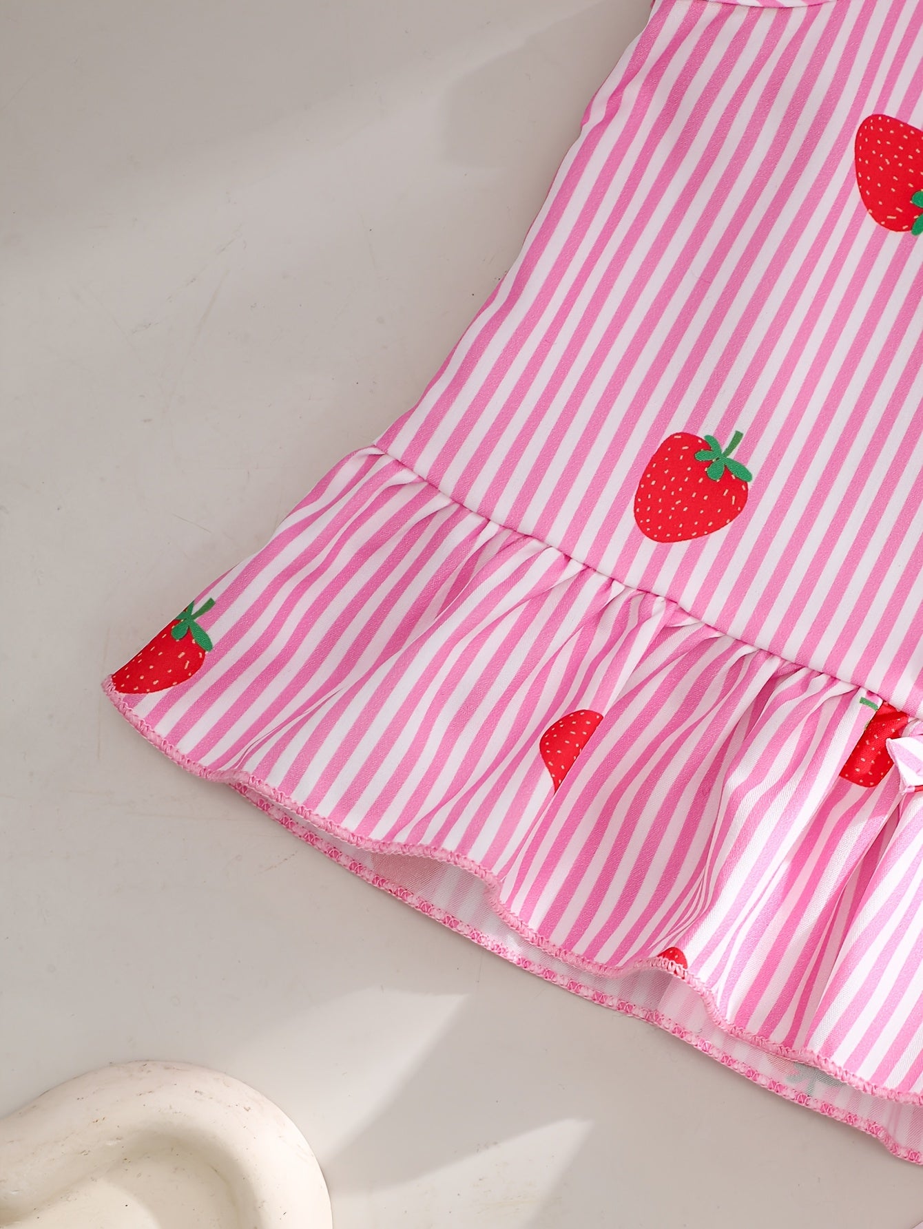 A Two-Piece Set. A Tank Top And Shorts Outfit Featuring Strawberry Prints, Striped Patterns, Bow Decorations, And a Ruffled Hem Design. This Is a Casual Summer Outfit for Girls. It Makes a Great Gift for Girls' Clothing. Suitable for Outdoor Wear