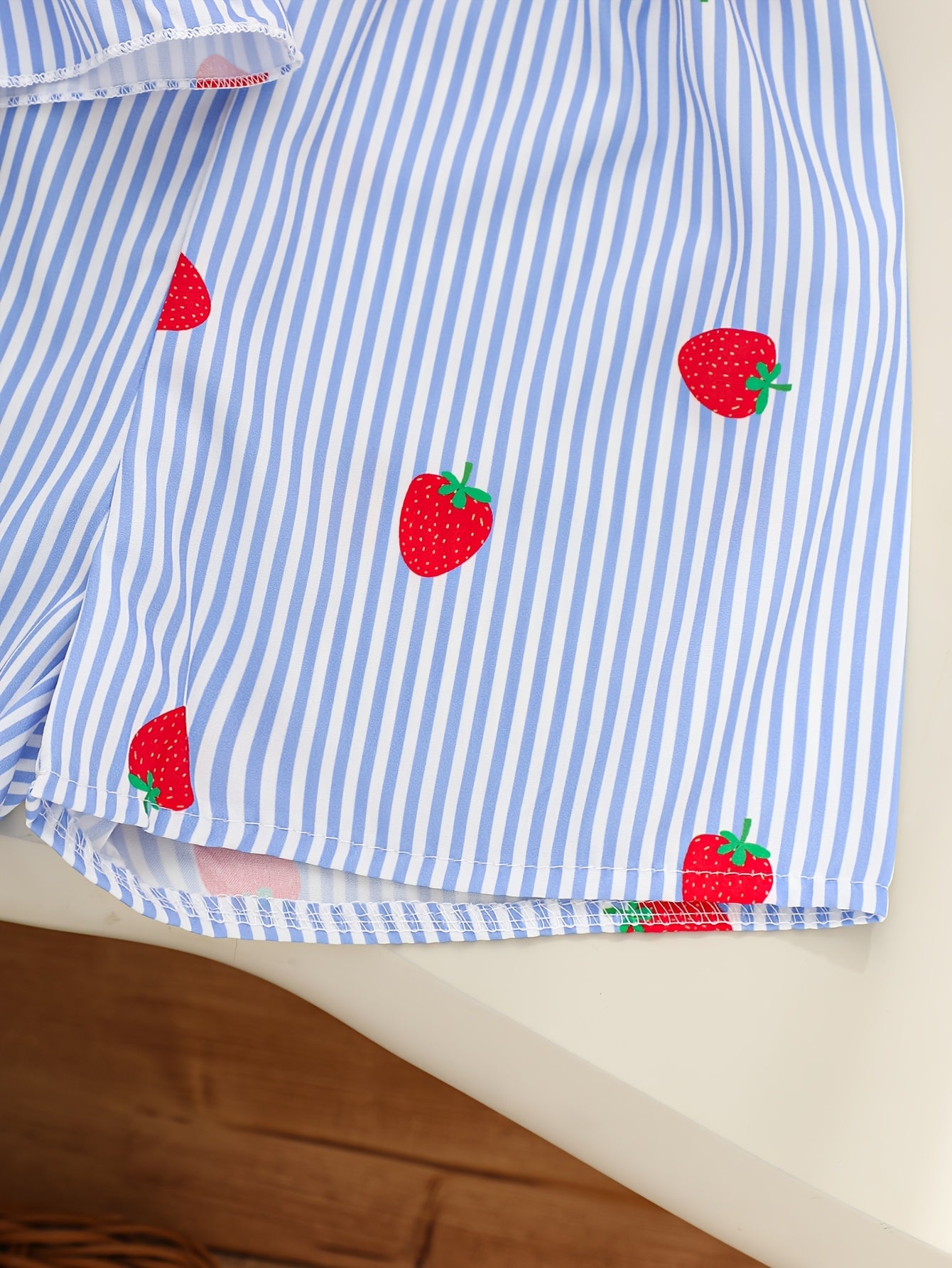 A Two-Piece Set. A Tank Top And Shorts Outfit Featuring Strawberry Prints, Striped Patterns, Bow Decorations, And a Ruffled Hem Design. This Is a Casual Summer Outfit for Girls. It Makes a Great Gift for Girls' Clothing. Suitable for Outdoor Wear